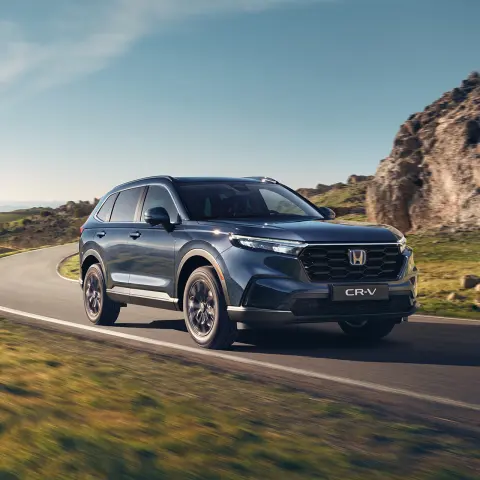 Voiture SUV hybride CR-V roulant sur une route de montagne.